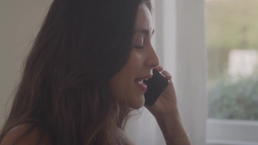 The woman nods her head while talking on the phone