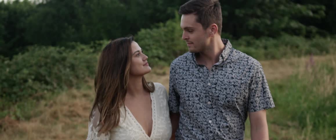 A couple walk down a field together