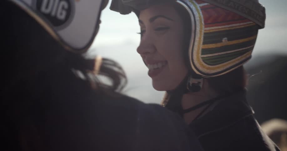 A man and woman wearing helmets talk