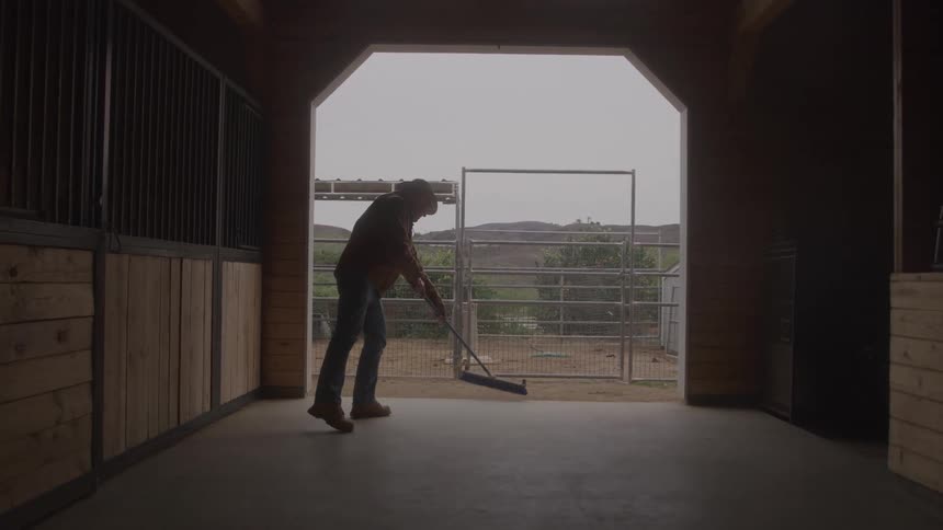 The man is sweeping the stables