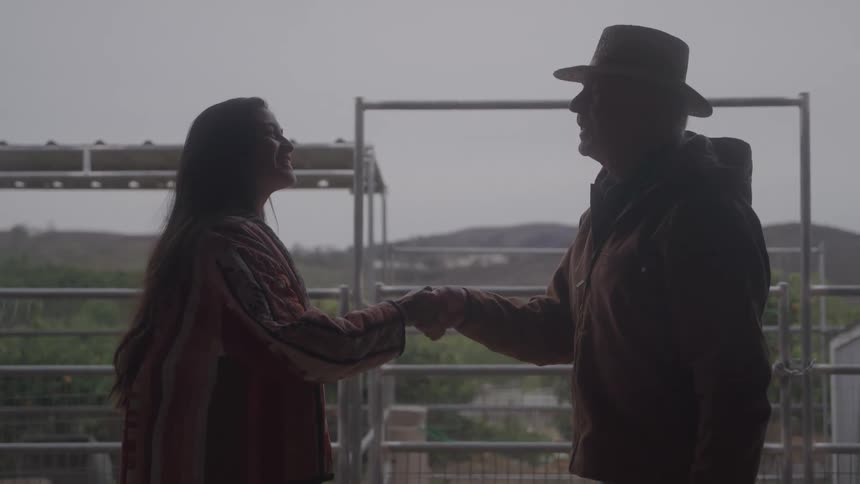 The man and woman shake hands on the ranch
