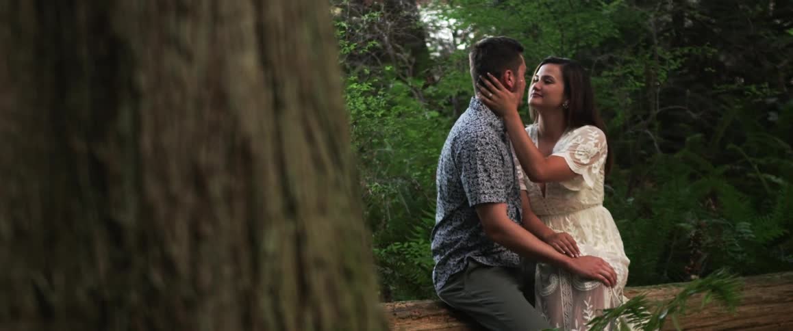 A man and woman kiss on a fallen log