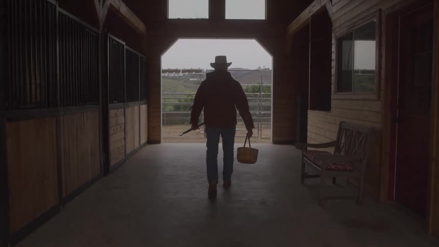 Farmer with a basket walking by a barn