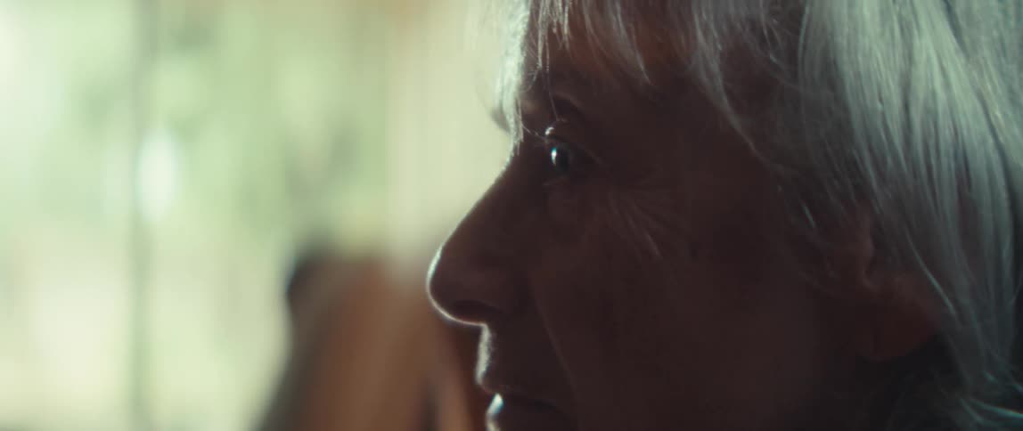 Profile of an elderly person with a serene expression in a softly lit indoor setting