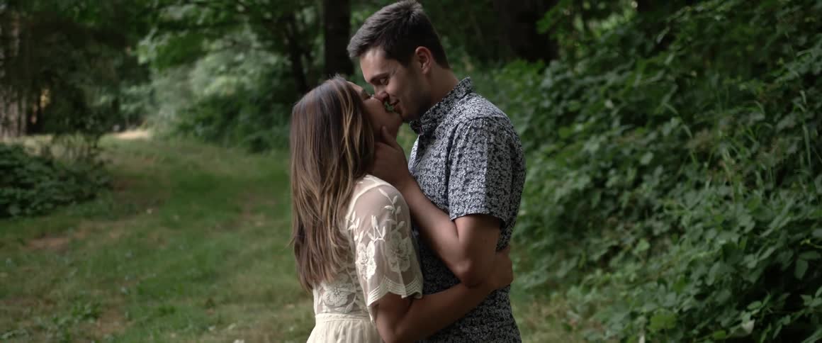 A man and woman are embracing and kissing in a natural setting
