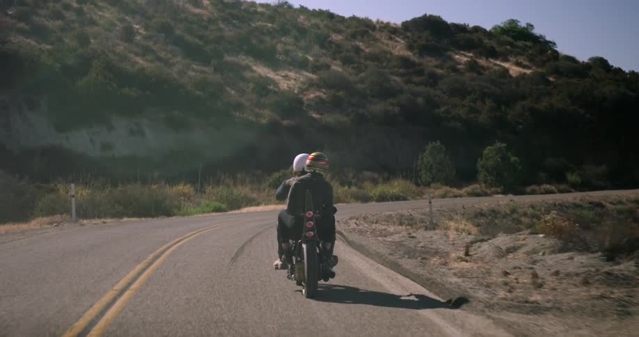 Two people riding a motorcycle wearing helmets