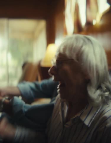 A joyful elderly couple enthusiastically plays video games together laughing and concentrating on their controllers