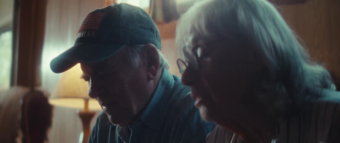 An elderly couple having a conversation while seated on a couch