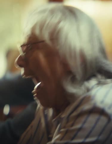 An older man and an older woman with gray hair show excited openmouthed expressions while actively playing a video game together indoors