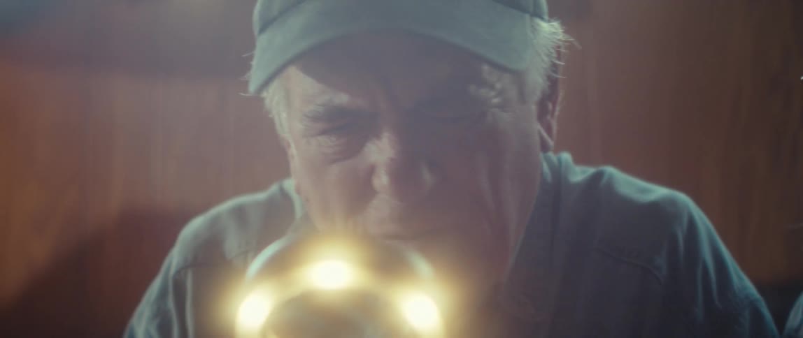A man inspects a puzzle piece under a magnifying glass