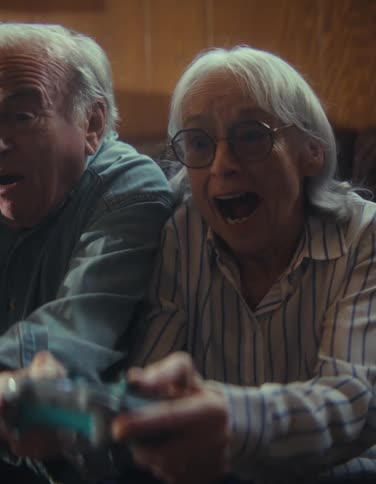 An elderly couple laughing while playing a video game indoors