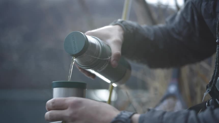 The man pours a hot drink from his thermos