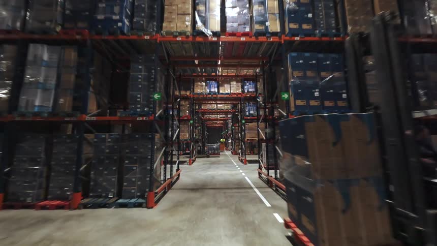 Industrial warehouse aisle with tall racks filled with stacked pallets