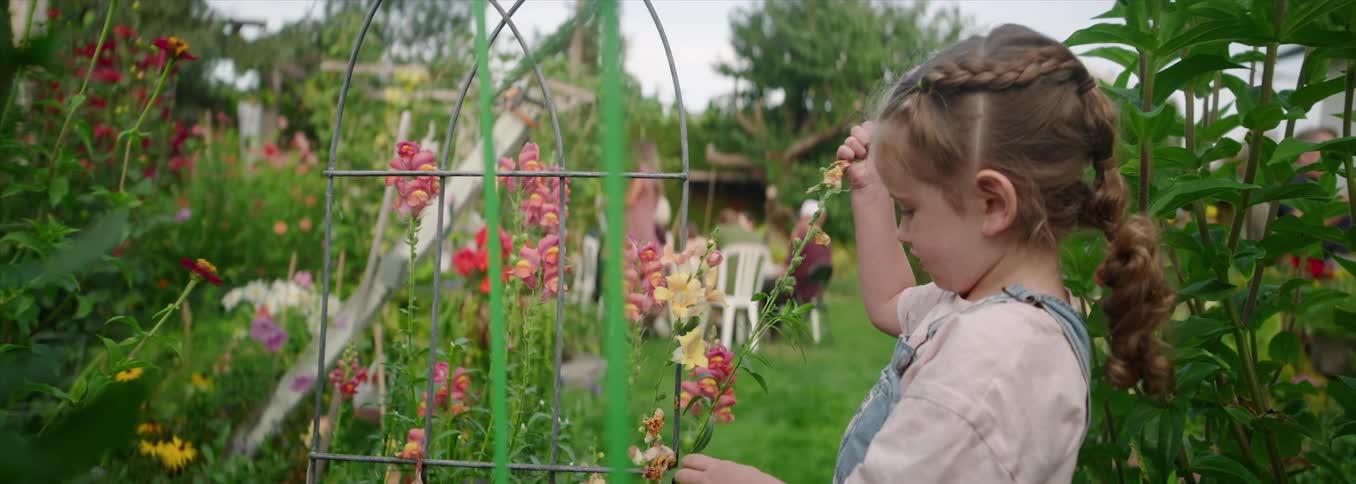 A young girl picking flowers in a backyard garden