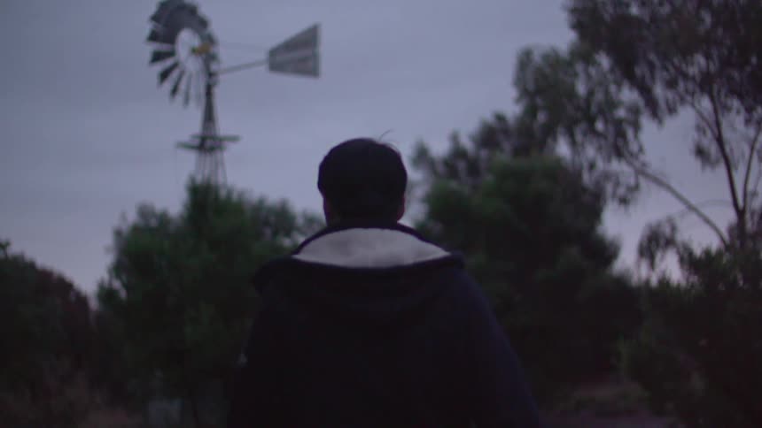 Man in hat walks by a windmill