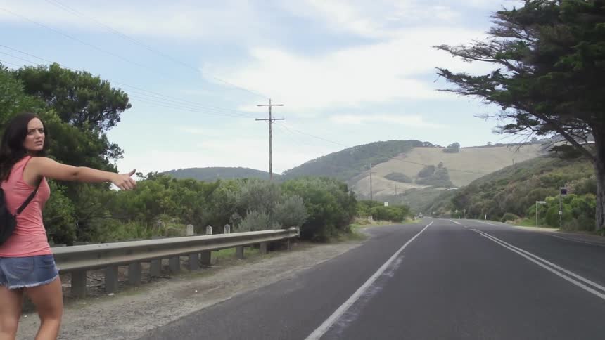 Woman hitchhiking on the side of the road