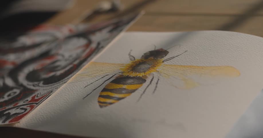 A detailed watercolor illustration of a bumblebee with yellow wings is featured in an open art book