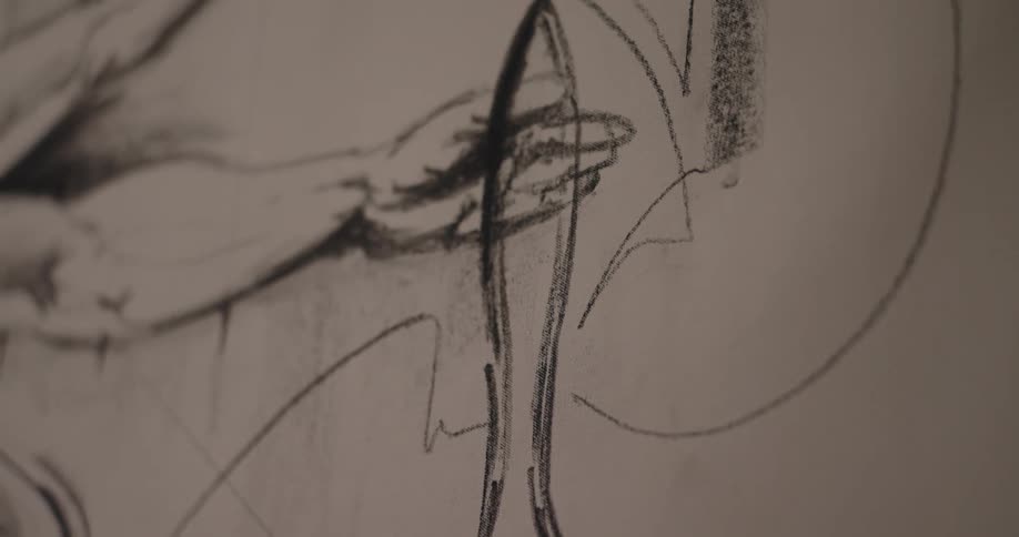 A close view shows charcoal lines rapidly sketching a large graphic rendering of a paintbrush onto a piece of white paper or canvas