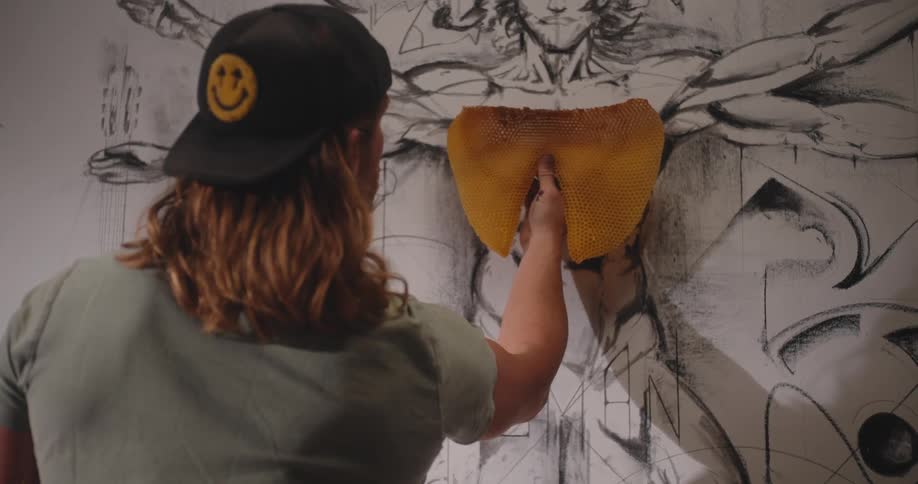 Person places a honeycomb onto a large artistic drawing of a human figure