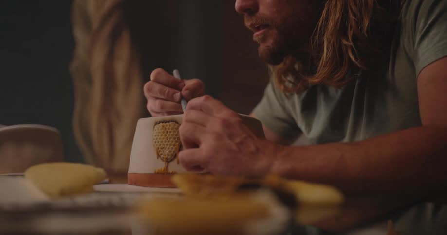 Man works on detailing a honeycomb attached to a cylindrical container