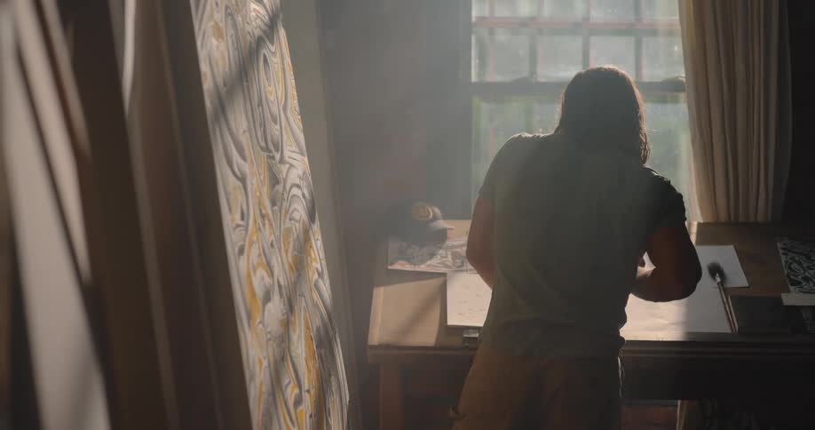 The man is sketching by the window