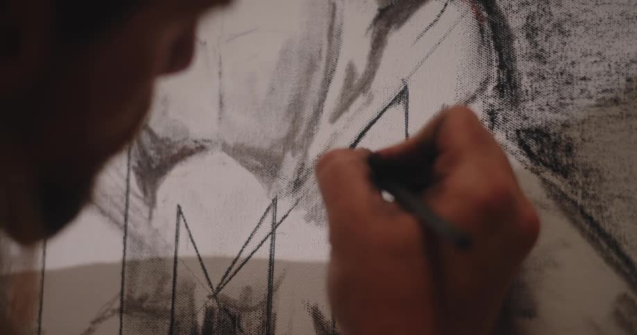 Male artist draws geometric shapes on a canvas with charcoal