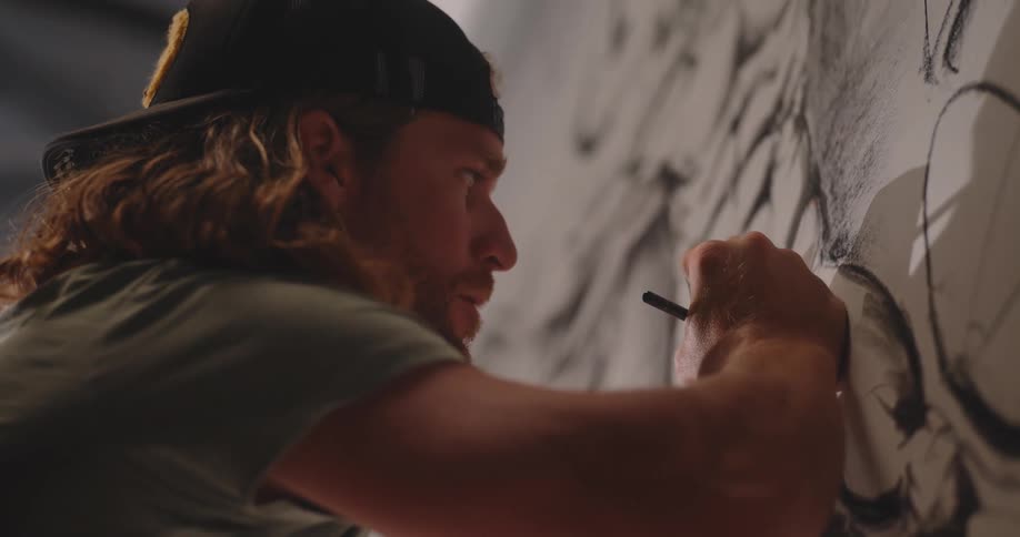 Man focuses while drawing details on a black and white mural