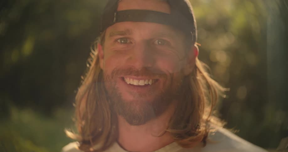 Smiling man wears a backward cap under the golden light of sunset