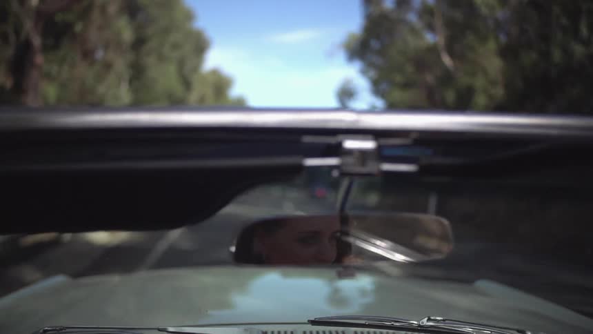 Convertible driving down a tree-lined road