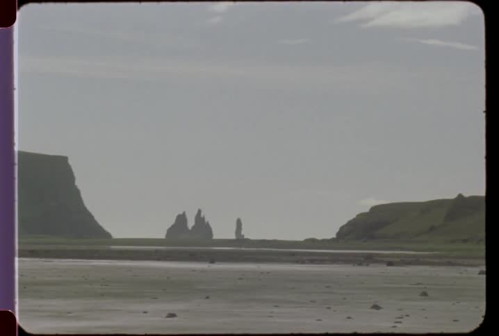 Three pointed rock structures stand in the distance across a dry lake bed