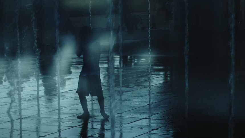 Silhouette of a child playing in a public fountain