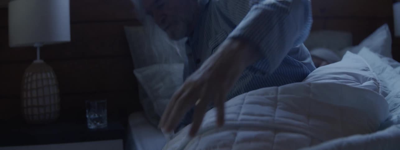 Man gets out of bed while the woman remains asleep