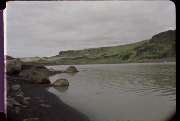 Water ripples past boulders by the shore