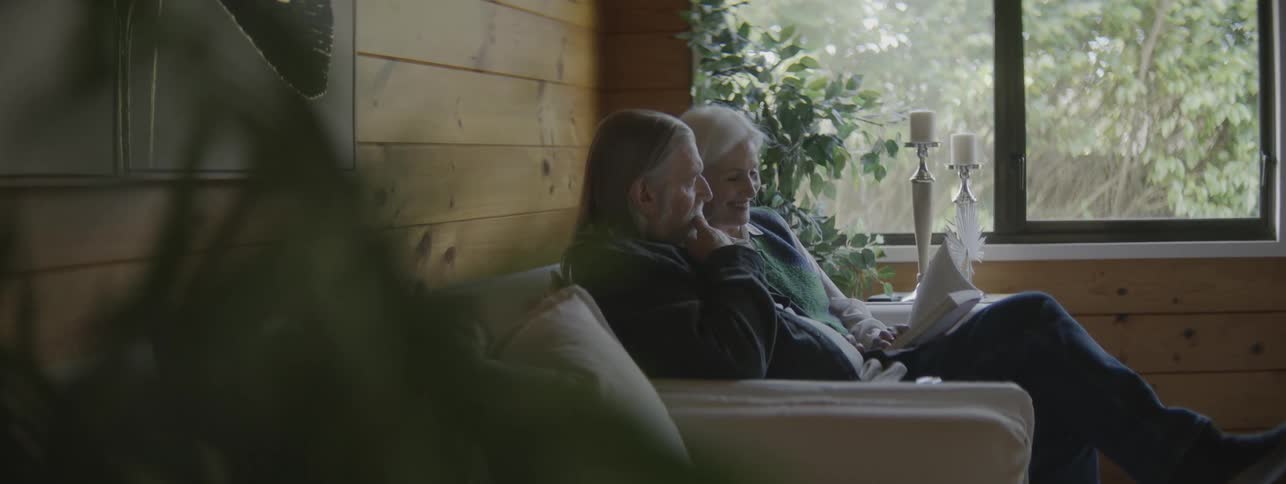 A man and woman sit together on the couch while reading