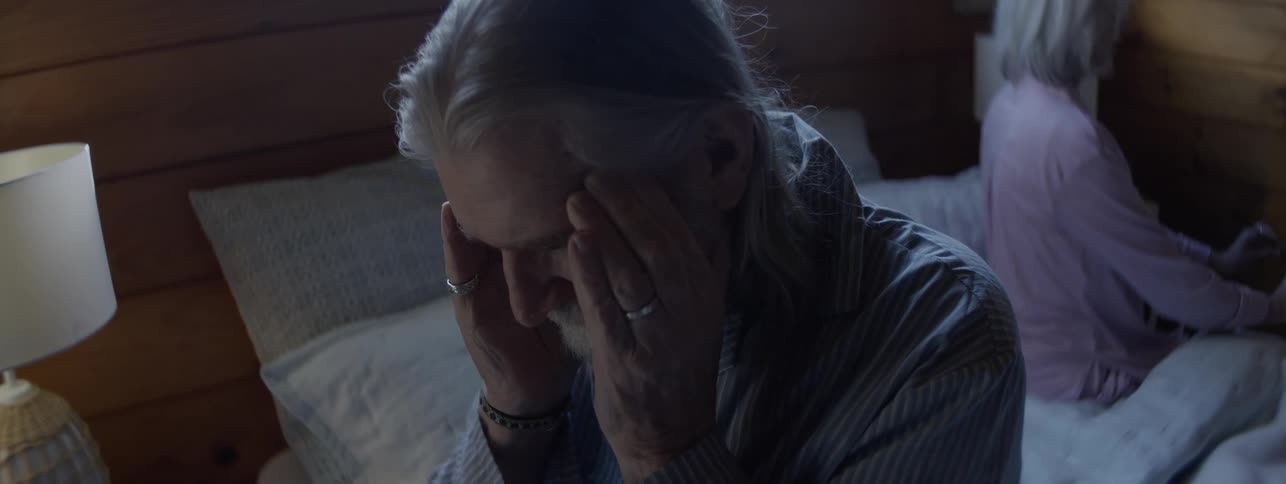 A sad couple argues over family conflict in a bedroom
