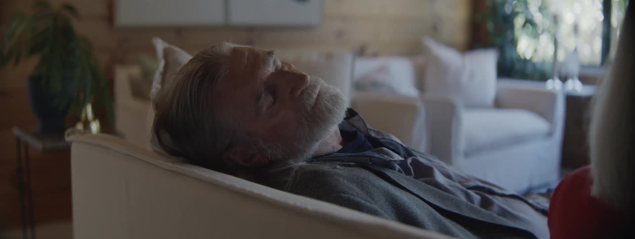 Man beginning to fall asleep on the couch next to a woman