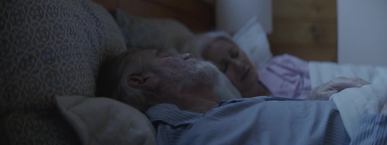 Man tossing and turning in bed next to a woman while they sleep