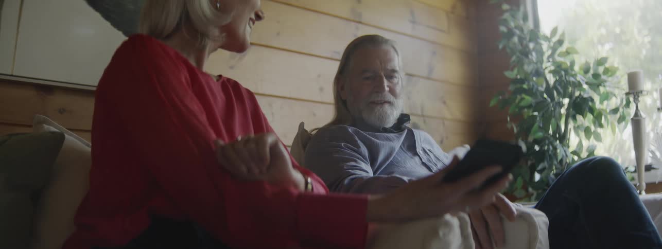 A woman holds a phone while she speaks to a man next to her