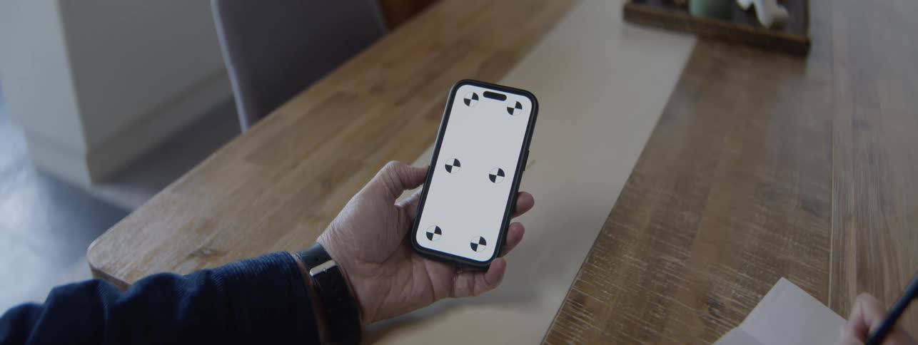 Man sitting at a table references his smartphone while making a note