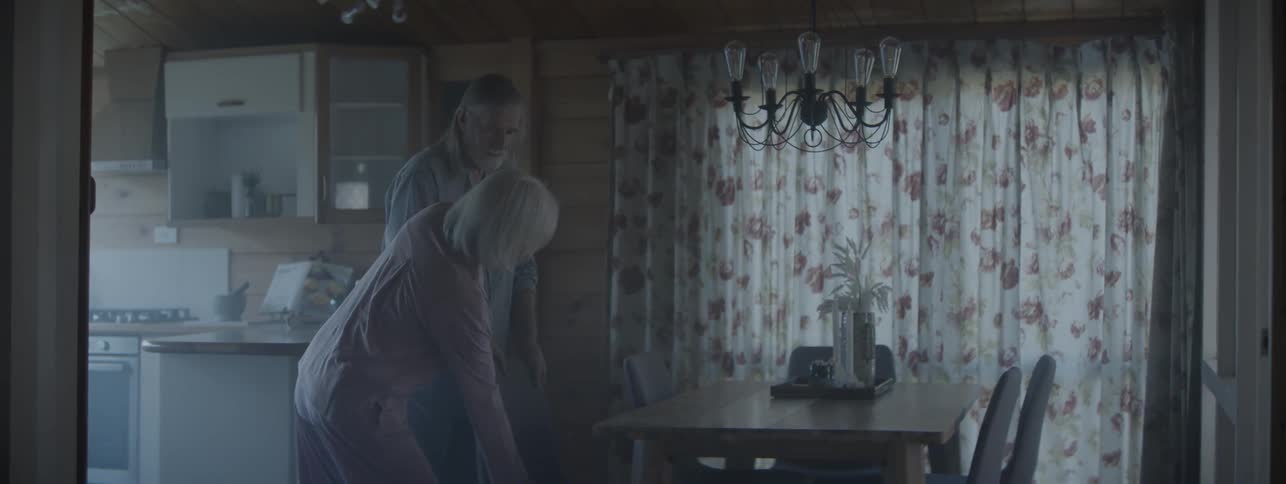 A confused elderly man with dementia is guided back to the bedroom after wandering off at night to hold his wife's chair for breakfast