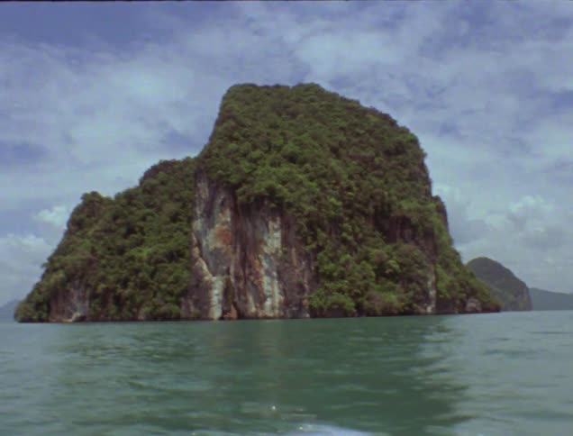 An island with a steep cliffside is surrounded by ocean water