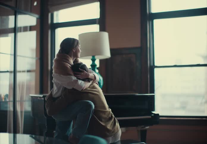 Couple hugging near a large window in a bright indoor setting