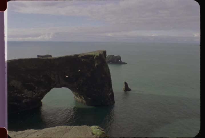 Birds fly past rock formations in the ocean