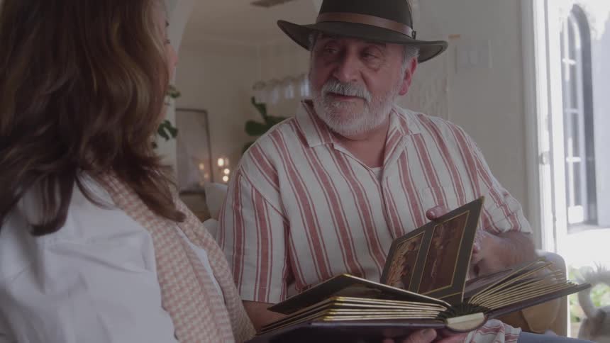 Close up of a middle aged couple conversing while reading together in a room during daytime