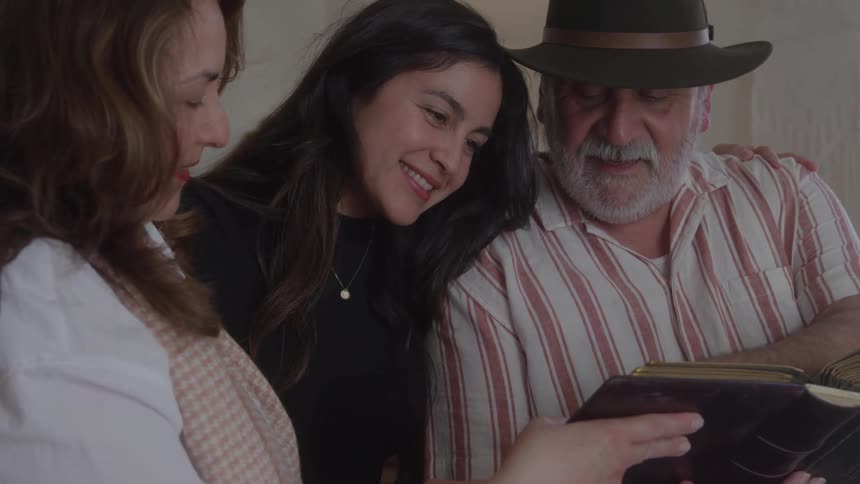 Family gathered smiles while flipping through a photo album together