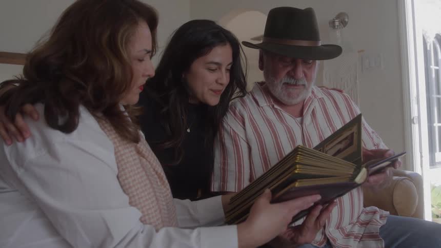 Grandparents flip through a photo album with their granddaughter