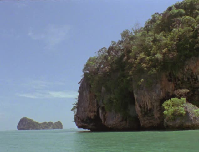 An island with steep cliff sides sits in the ocean