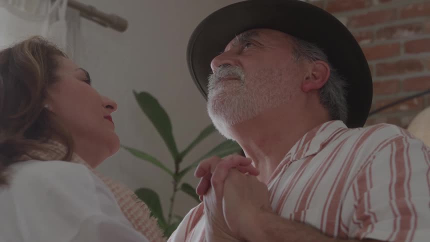 Couple dances together exchanging glances with intertwined hands