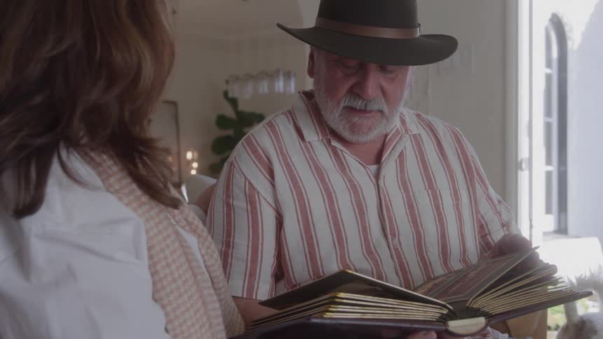 Man wearing a hat flipping through an album beside a woman