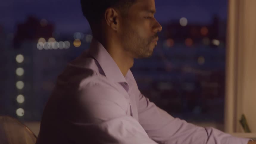 Man typing on a laptop at a welllit desk at night